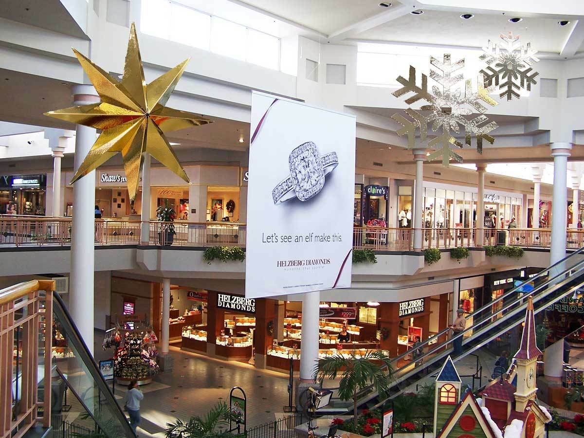 Large snowflakes and advertisments hanging from the ceiling of a mall
