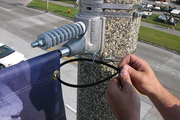 Adding zip ties to the banner saver bracket to install it on a street light.